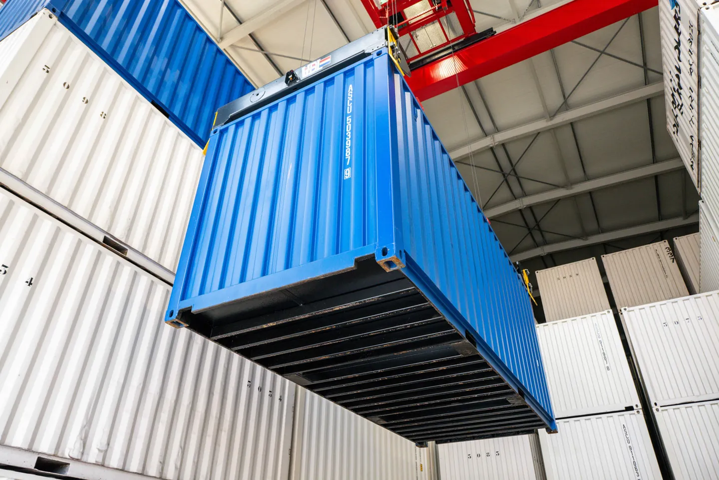 Blauwe opslagcontainer wordt met de kraan in de containerloods geplaatst