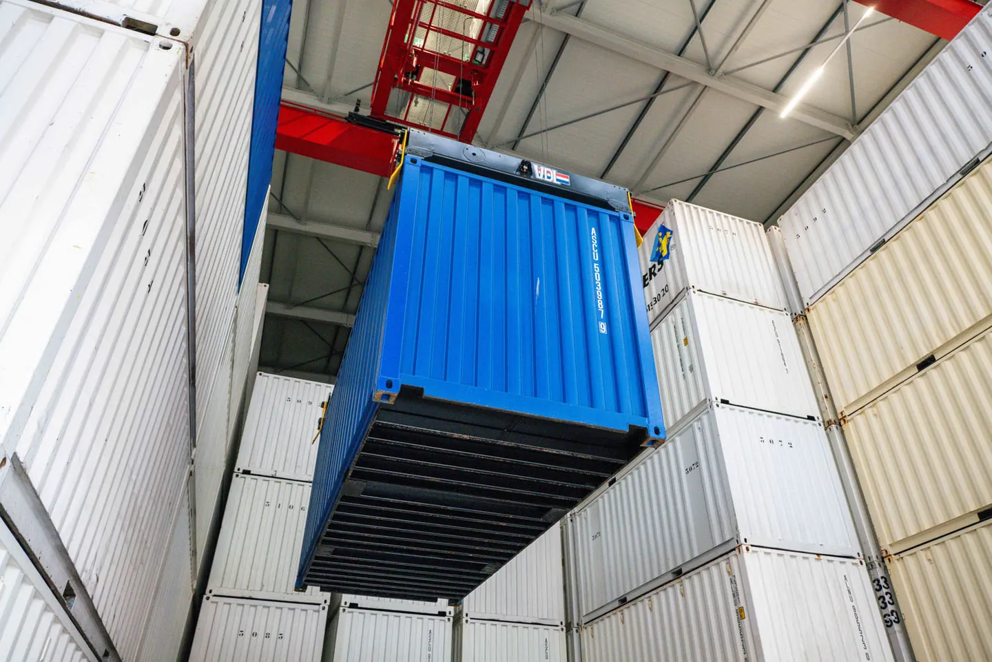 Blauwe opslagcontainer tussen de gestapelde containers in de containerloods